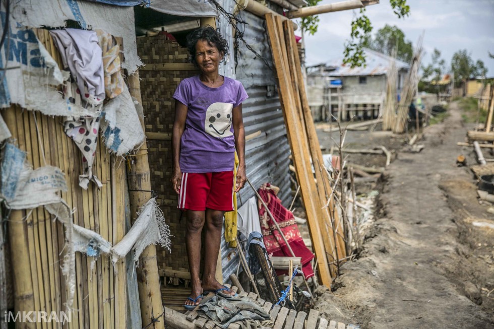 Local lady stands in front of her home when we pass. Most homes have been rebuild using the spare parts from old houses. She still lives with no electricity
